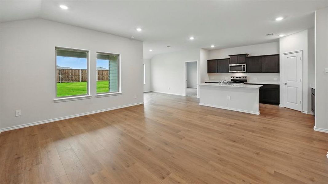 Kitchen with open floor plan, a kitchen island with sink, stainless steel appliances, light wood finished floors, and recessed lighting