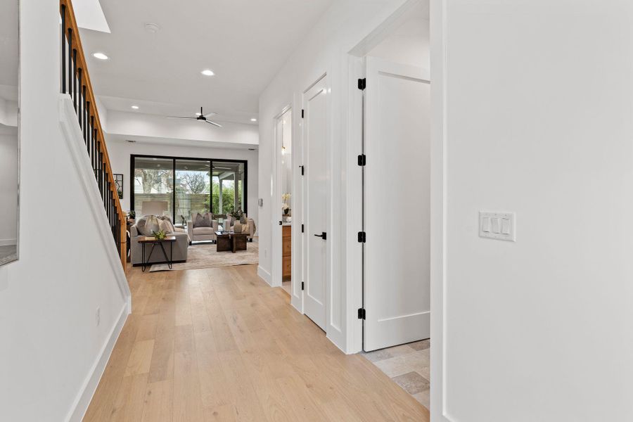 Hallway with recessed lighting, light wood-style flooring, baseboards, and stairs