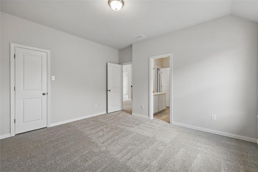 Unfurnished bedroom featuring light carpet and connected bathroom