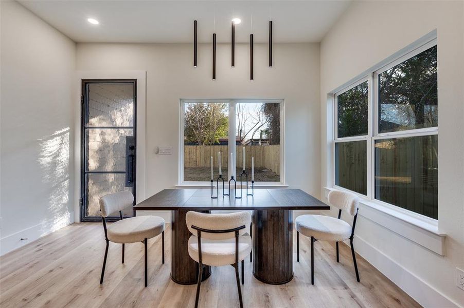 Spacious room featuring light wood-finish flooring, white walls, and a contemporary linear pendant light fixture