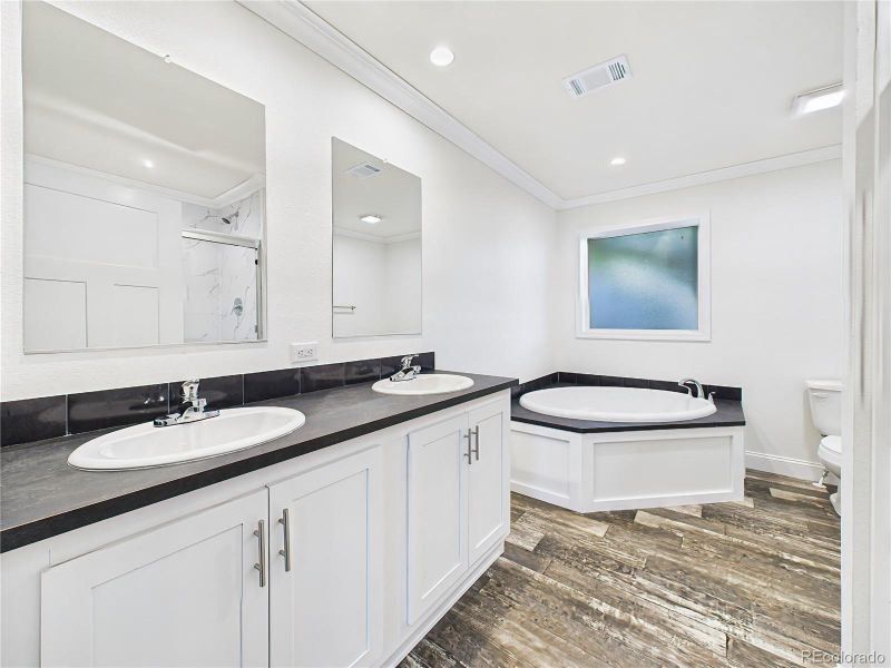 Relaxing corner soaking tub and separate walk-in shower with marble-look tile surround.