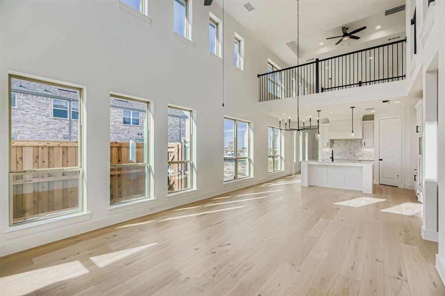 Unfurnished living room with light wood-style floors, ceiling fan, recessed lighting, and a chandelier Unfurnished living room with light wood-style floors, ceiling fan, recessed lighting, and a chandelier