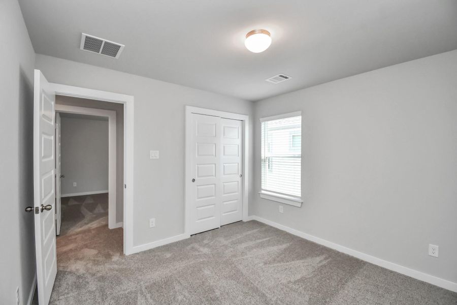 Generously sized secondary bedrooms featuring spacious closets, soft and inviting carpeting underfoot, large windows allowing plenty of natural light, and the added touch of privacy blinds for your personal retreat. Sample photo of completed home with similar floor plan. Actual colors and selections may vary.