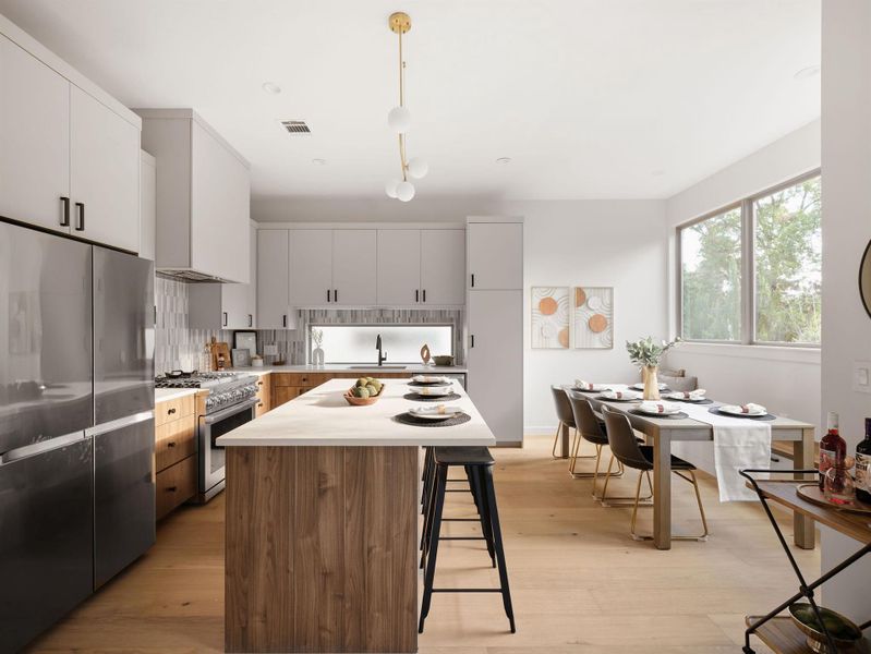 Kitchen with appliances with stainless steel finishes, light countertops, a breakfast bar, light wood finished floors, and decorative backsplash