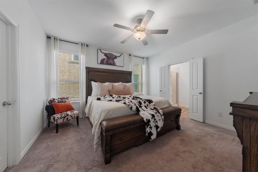 Bedroom with multiple windows, light colored carpet, and ceiling fan