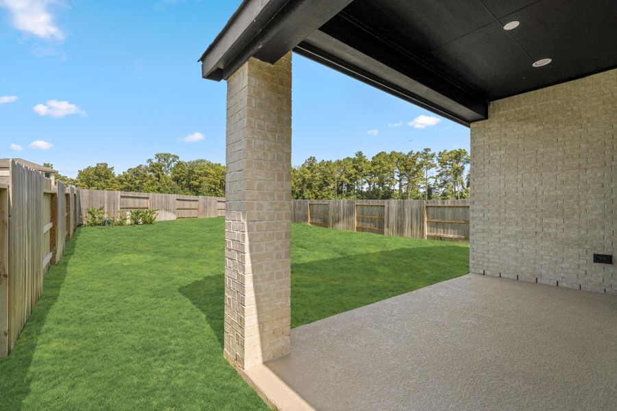 Covered back patio overlooking the large fenced yard, ideal for shaded outdoor living.