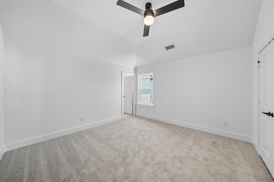 Unfurnished bedroom with light colored carpet, a ceiling fan, and vaulted ceiling