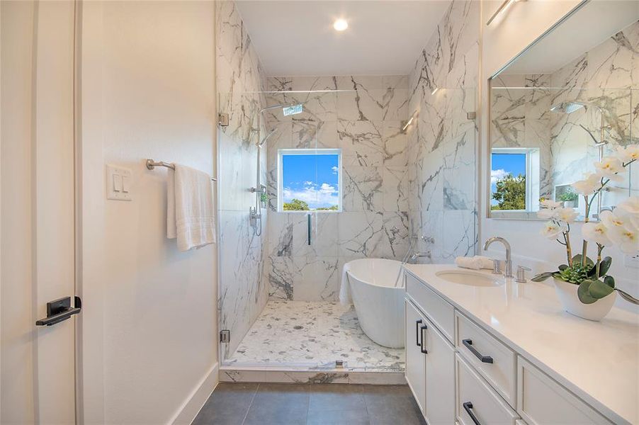 Bathroom featuring a marble finish shower, a freestanding tub, vanity, and dark tile patterned floors Bathroom featuring a marble finish shower, a freestanding tub, vanity, and dark tile patterned floors