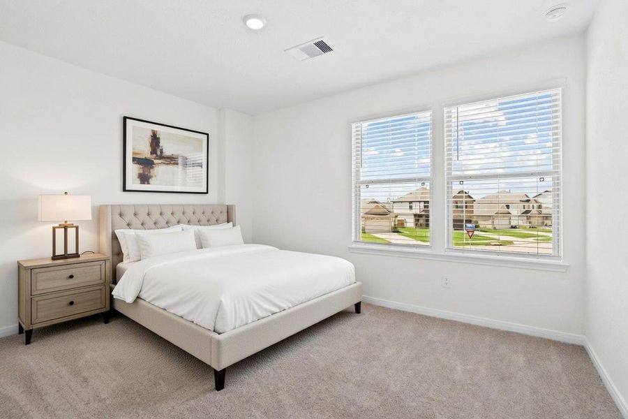This secondary bedroom combines comfort and style, featuring plush carpeting, neutral paint, recessed lighting, large windows with blinds, and a spacious closet.