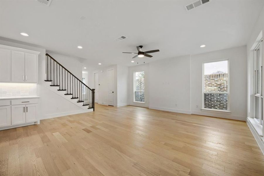 Bright open-concept living space with light wood-finish flooring, recessed lighting, and a modern ceiling fan Bright open-concept living space with light wood-finish flooring, recessed lighting, and a modern ceiling fan