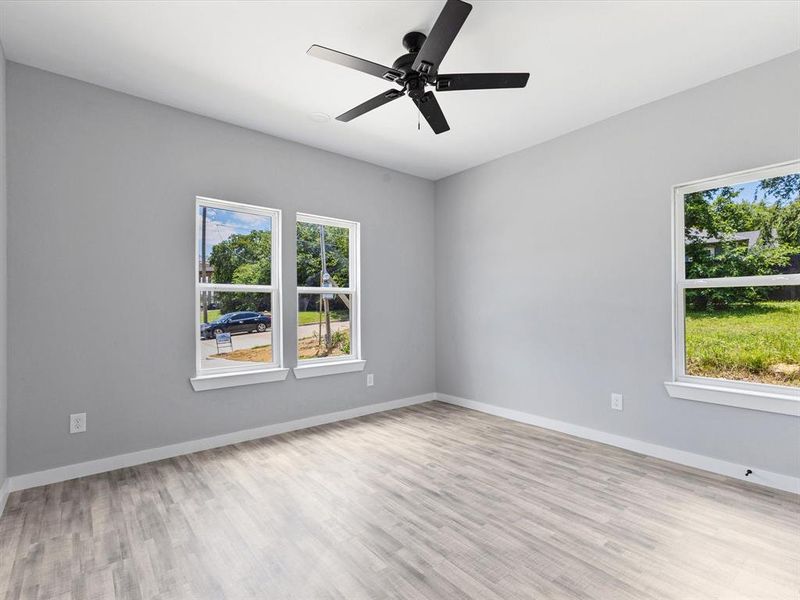Empty room with healthy amount of natural light, wood finished floors, a ceiling fan, and baseboards