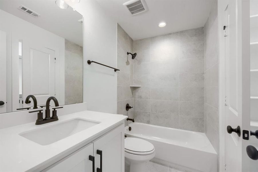 Bathroom featuring a white vanity with an integrated sink, dark bronze fixtures, light gray subway tile shower surround with a built-in niche, and recessed lighting