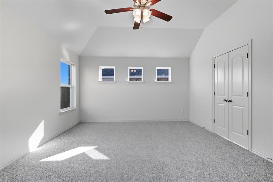 Unfurnished bedroom with vaulted ceiling, light colored carpet, a ceiling fan, and a closet Unfurnished bedroom with vaulted ceiling, light colored carpet, a ceiling fan, and a closet