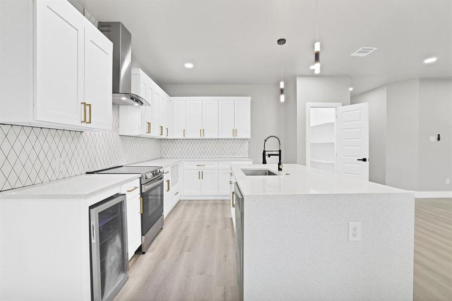 Kitchen with beverage cooler, appliances with stainless steel finishes, decorative light fixtures, white cabinets, and light wood-type flooring