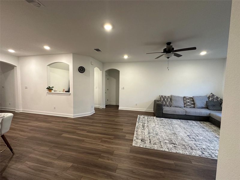 Spacious living area featuring wood-finish flooring, recessed lighting, and a ceiling fan Spacious living area featuring wood-finish flooring, recessed lighting, and a ceiling fan