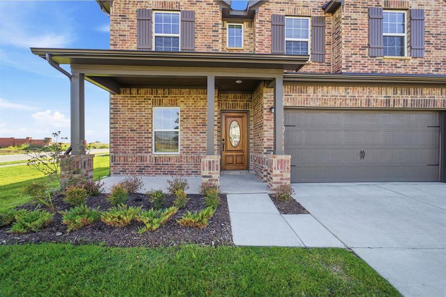Brick exterior featuring a covered front porch with substantial columns, a wood-finish entry door with an oval glass insert, and decorative window shutters Brick exterior featuring a covered front porch with substantial columns, a wood-finish entry door with an oval glass insert, and decorative window shutters