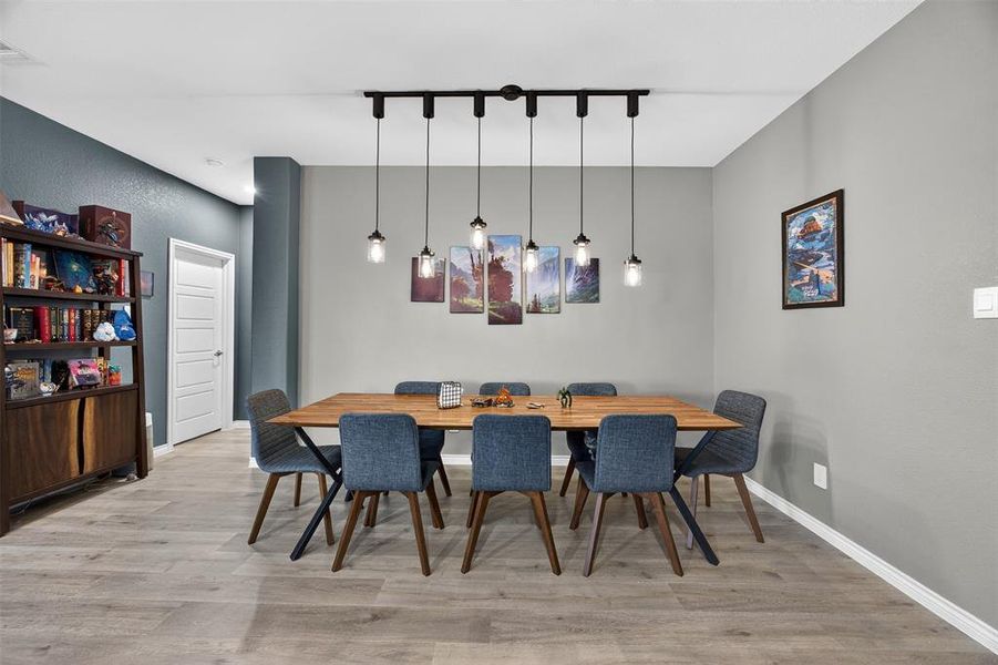 Dining area with light wood-style floors and rail lighting