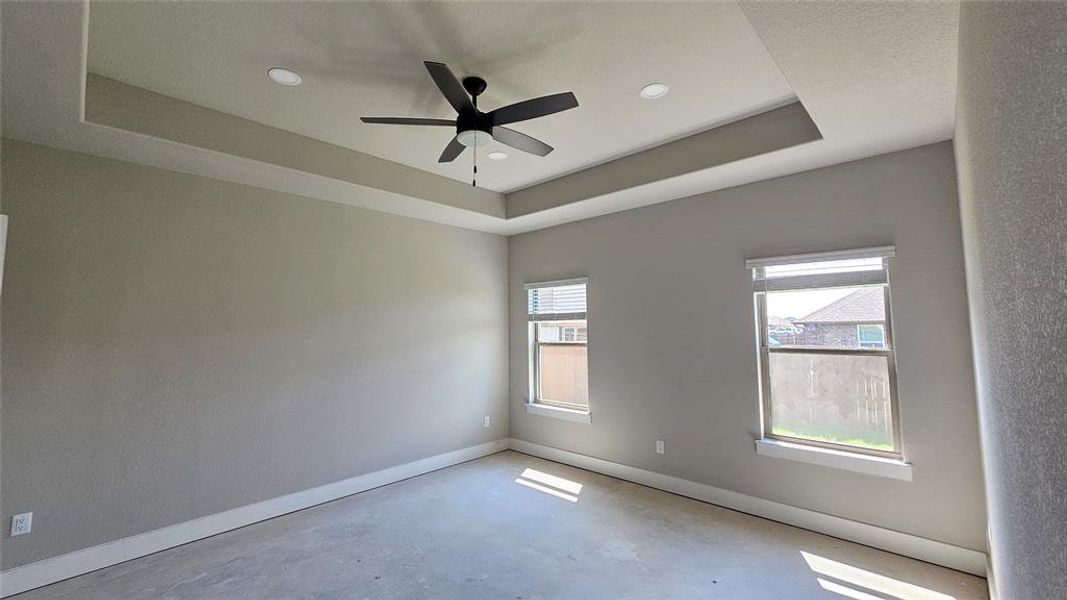 Unfurnished room with ceiling fan and a tray ceiling