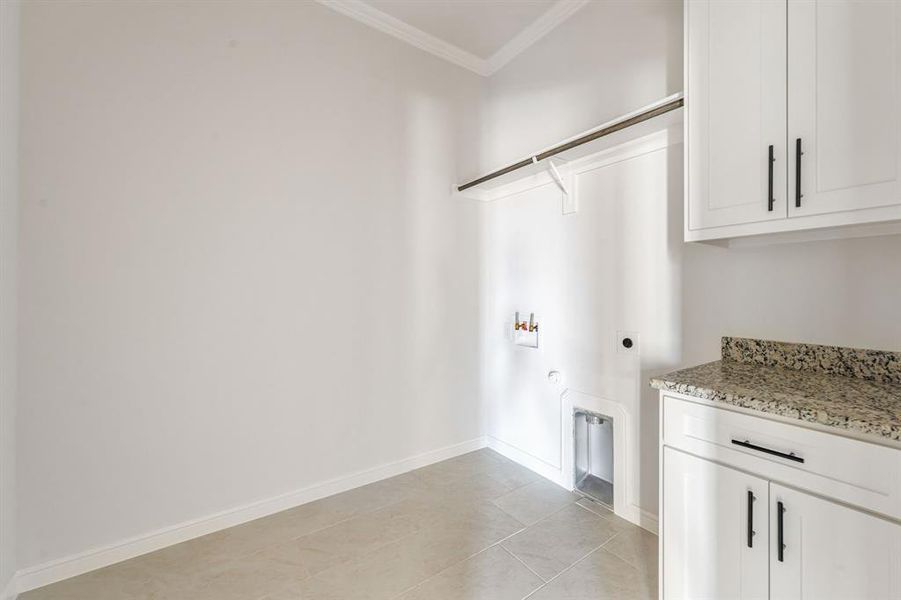 Laundry room with hookup for a gas dryer, washer hookup, ornamental molding, light tile patterned floors, and electric dryer hookup