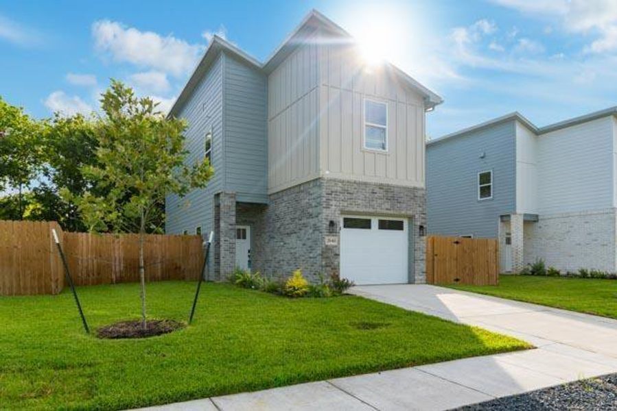 Contemporary home with board and batten siding, an attached garage, driveway, and brick siding Contemporary home with board and batten siding, an attached garage, driveway, and brick siding