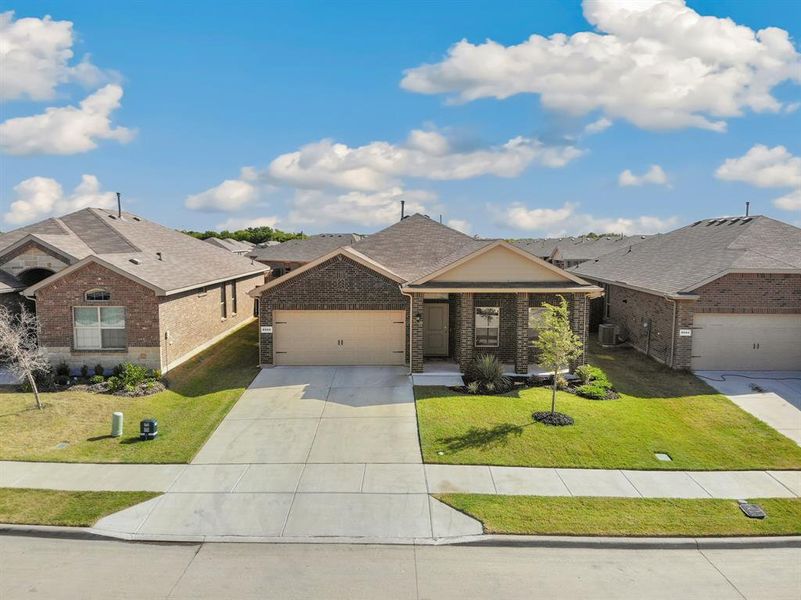 View of front of house with brick siding, driveway, a front lawn, an attached garage, and a shingled roof