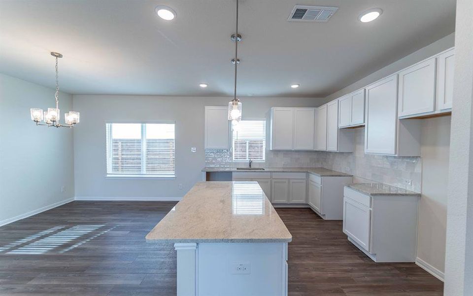 Kitchen featuring a large island with a light-colored countertop, white shaker cabinetry, a subway tile backsplash, and recessed lighting