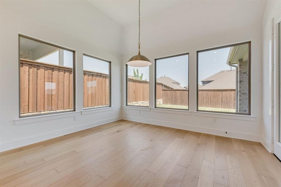 Unfurnished dining area featuring light wood finished floors and vaulted ceiling