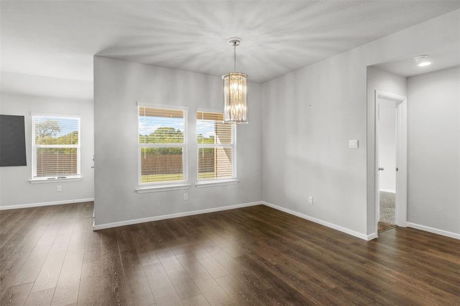 Unfurnished room with an inviting chandelier and dark hardwood / wood-style flooring