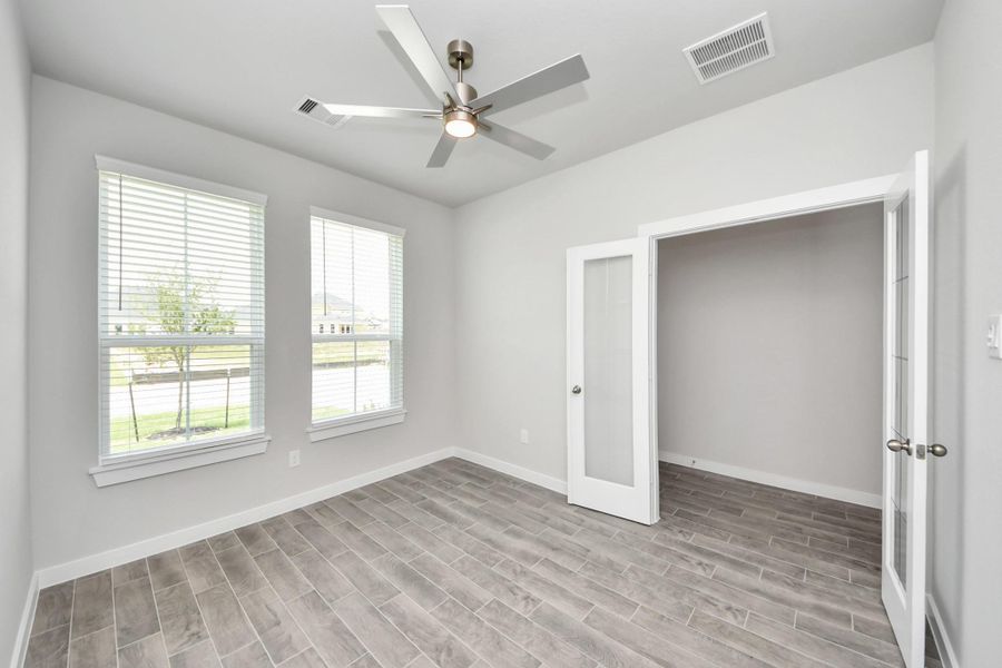 Experience the perfect blend of sophistication and warmth in this home office, boasting elegant wood-look tile flooring and flooded with natural light from expansive windows and French doors. Sample photo of completed home with similar floor plan. Actual colors and selections may vary. Experience the perfect blend of sophistication and warmth in this home office, boasting elegant wood-look tile flooring and flooded with natural light from expansive windows and French doors. Sample photo of completed home with similar floor plan. Actual colors and selections may vary.