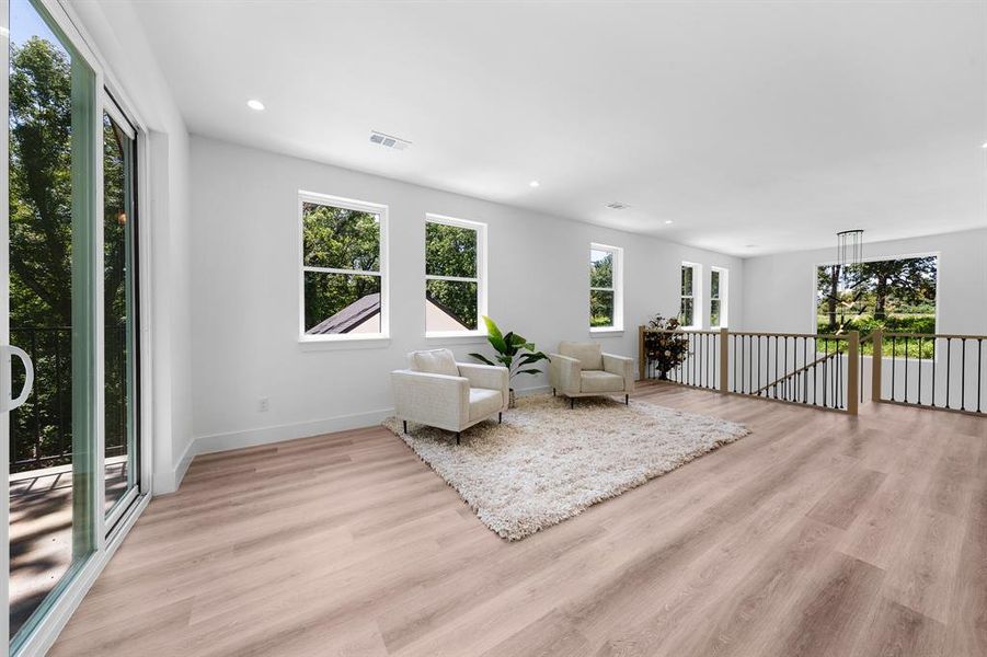 Living area featuring light wood-style flooring, recessed lighting, and an upstairs landing Living area featuring light wood-style flooring, recessed lighting, and an upstairs landing