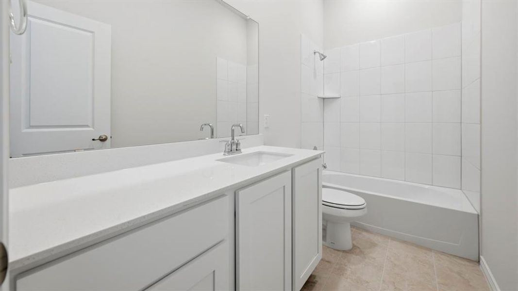 Bathroom featuring a white vanity with an integrated sink and chrome faucet, a large wall-mounted mirror, a white bathtub with subway tile surround, and neutral-toned floor tiling