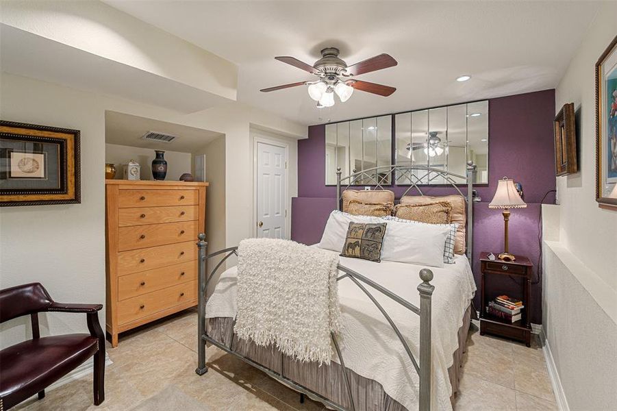 Inviting room featuring a decorative accent wall, tiled flooring, ceiling fan with integrated lighting, and a solid core door