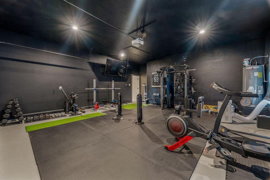 Exercise room with finished concrete flooring, water heater, and a garage Exercise room with finished concrete flooring, water heater, and a garage
