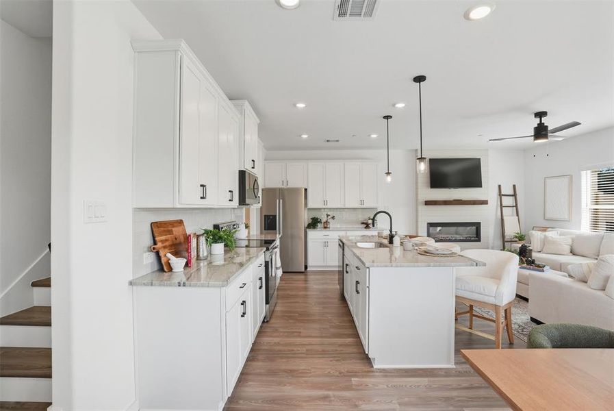 Kitchen with open floor plan, hanging light fixtures, stainless steel appliances, recessed lighting, and light stone countertops Kitchen with open floor plan, hanging light fixtures, stainless steel appliances, recessed lighting, and light stone countertops