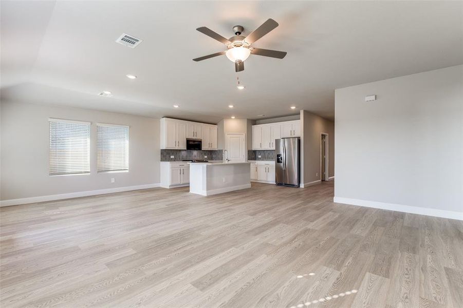 Unfurnished living room with light wood-style floors, ceiling fan, and recessed lighting