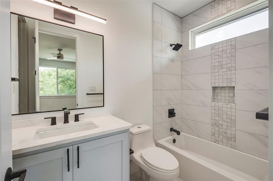 Full bathroom featuring tiled shower / bath, toilet, and vanity