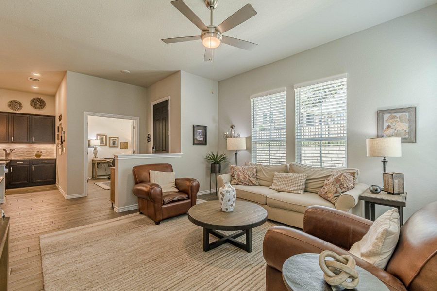 Living area with light wood-style flooring, a ceiling fan, and baseboards