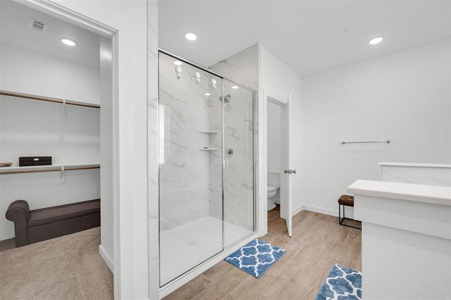 Bathroom featuring wood-type flooring, toilet, and a shower with shower door