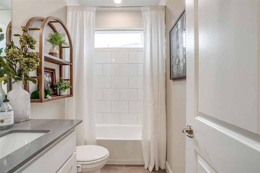 Bathroom with toilet, shower / tub combo with curtain, and vanity