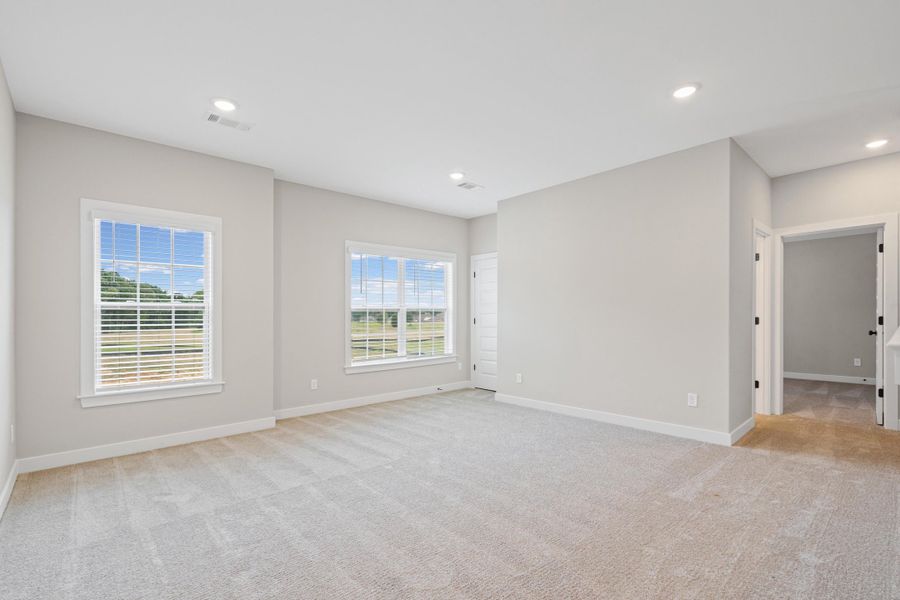 Spacious carpeted room with light gray walls, two double-hung windows, recessed ceiling lighting, and white baseboards Spacious carpeted room with light gray walls, two double-hung windows, recessed ceiling lighting, and white baseboards