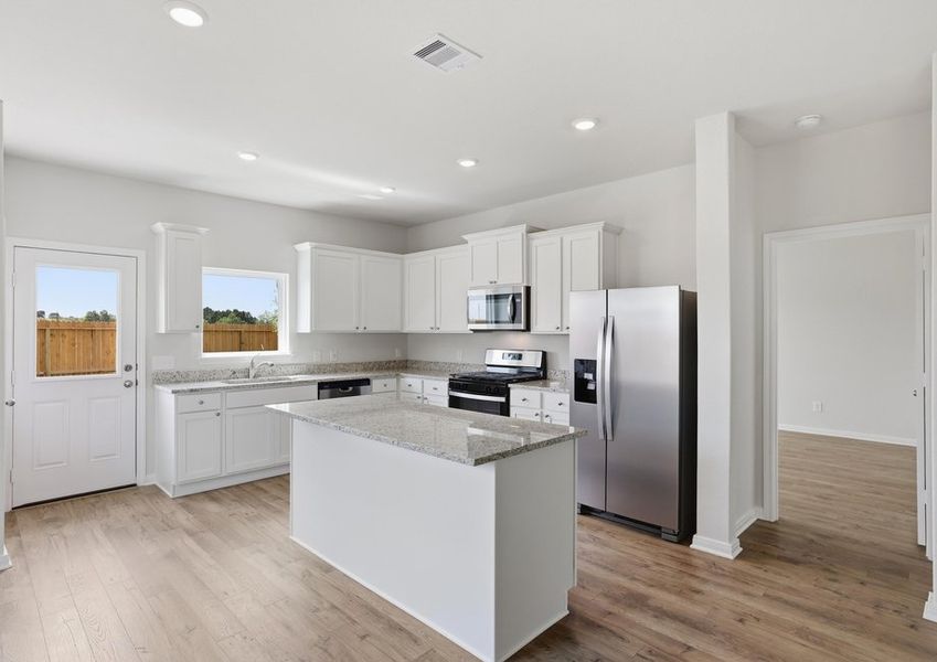 Kitchen featuring a granite island, stainless range, and white cabinetry.