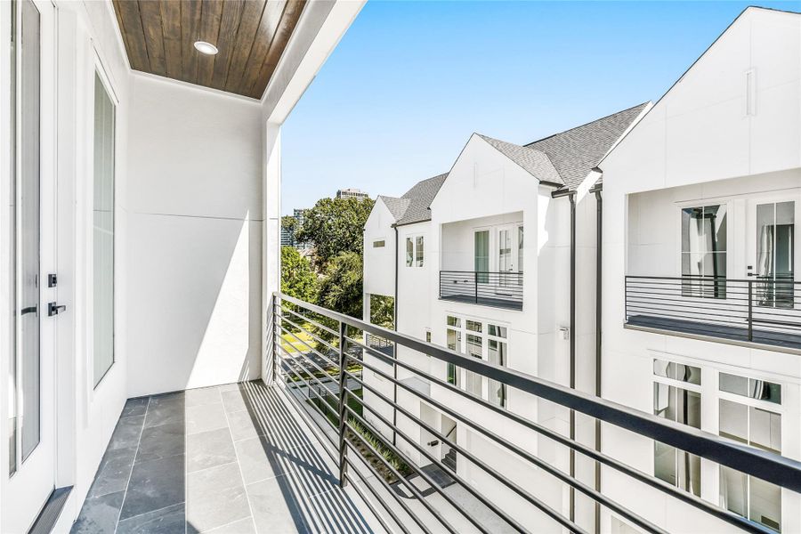 Step through French doors to your private, covered balcony, an intimate escape designed for fresh-air moments and morning coffee. Featuring slate tile flooring, modern iron railing, and a wood-accented ceiling with recessed lighting, this outdoor space extends the serenity of the primary suite—perfectly blending indoor comfort with outdoor ease in the heart of Houston’s urban luxury.