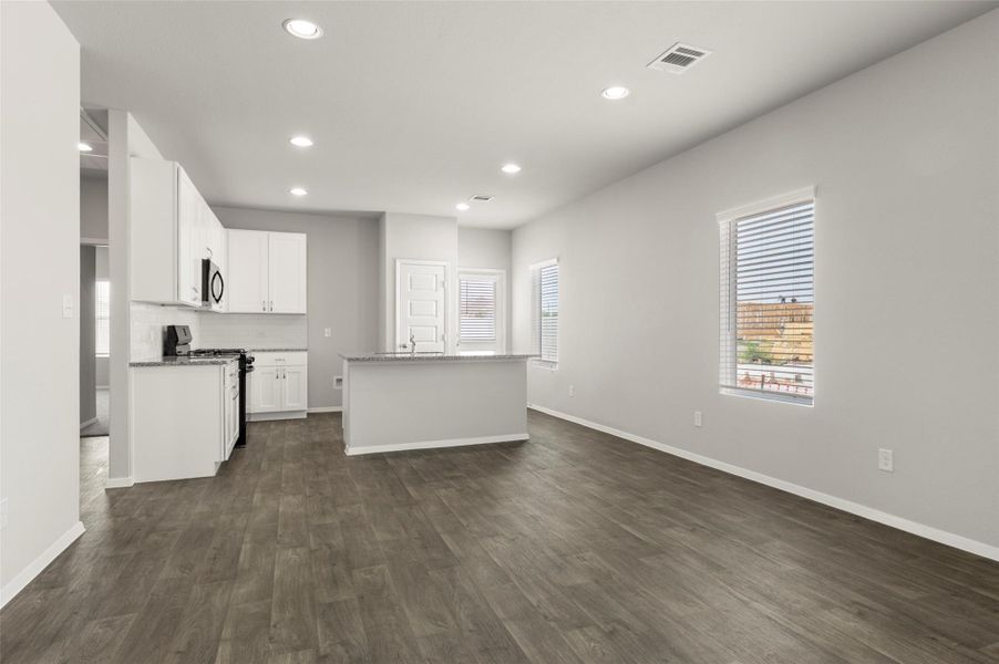 Kitchen featuring range with gas stovetop, recessed lighting, dark wood-style flooring, a kitchen island with sink, and white cabinetry