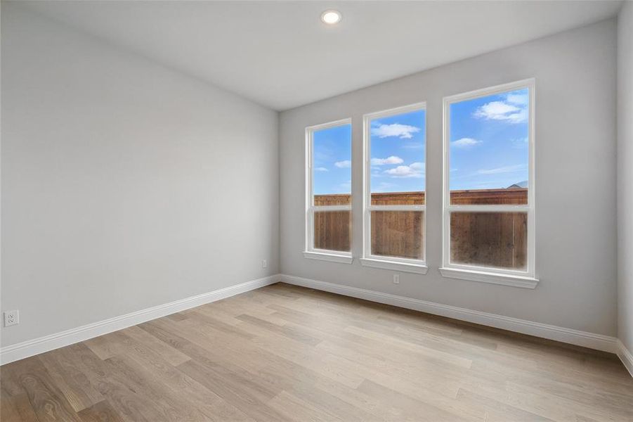 Spare room with baseboards, light wood-style floors, and recessed lighting