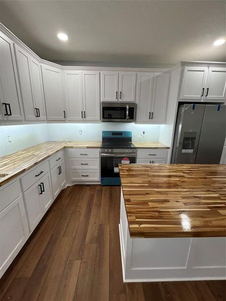 Kitchen featuring butcher block countertops, white cabinets, white fridge, and recessed lighting Kitchen featuring butcher block countertops, white cabinets, white fridge, and recessed lighting