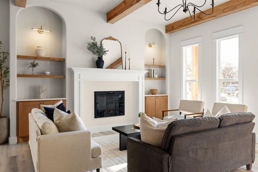 Living room featuring beam ceiling, light hardwood / wood-style floors, an inviting chandelier, and built in shelves