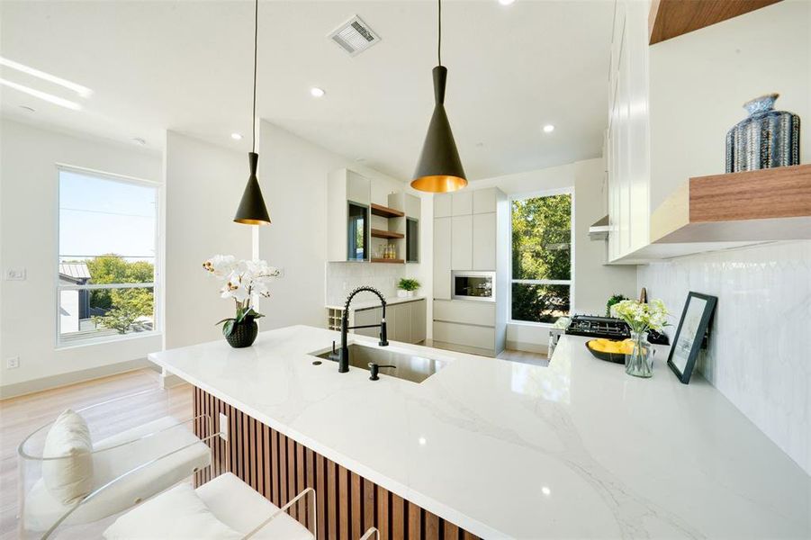 Kitchen with sink, light hardwood / wood-style flooring, decorative light fixtures, and white cabinets