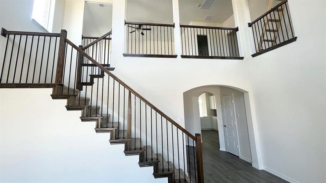 Stairway with arched walkways, a high ceiling, and wood finished floors Stairway with arched walkways, a high ceiling, and wood finished floors