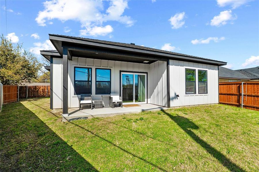 Rear view of house featuring a Covered patio area, a fenced backyard, and board and batten siding