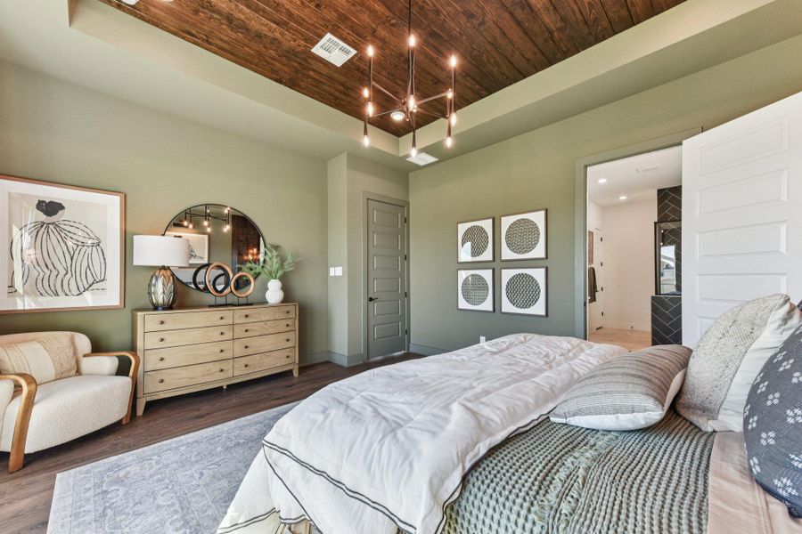 Rich wood-paneled tray ceilings and warm hardwood floors create a welcoming bedroom retreat.